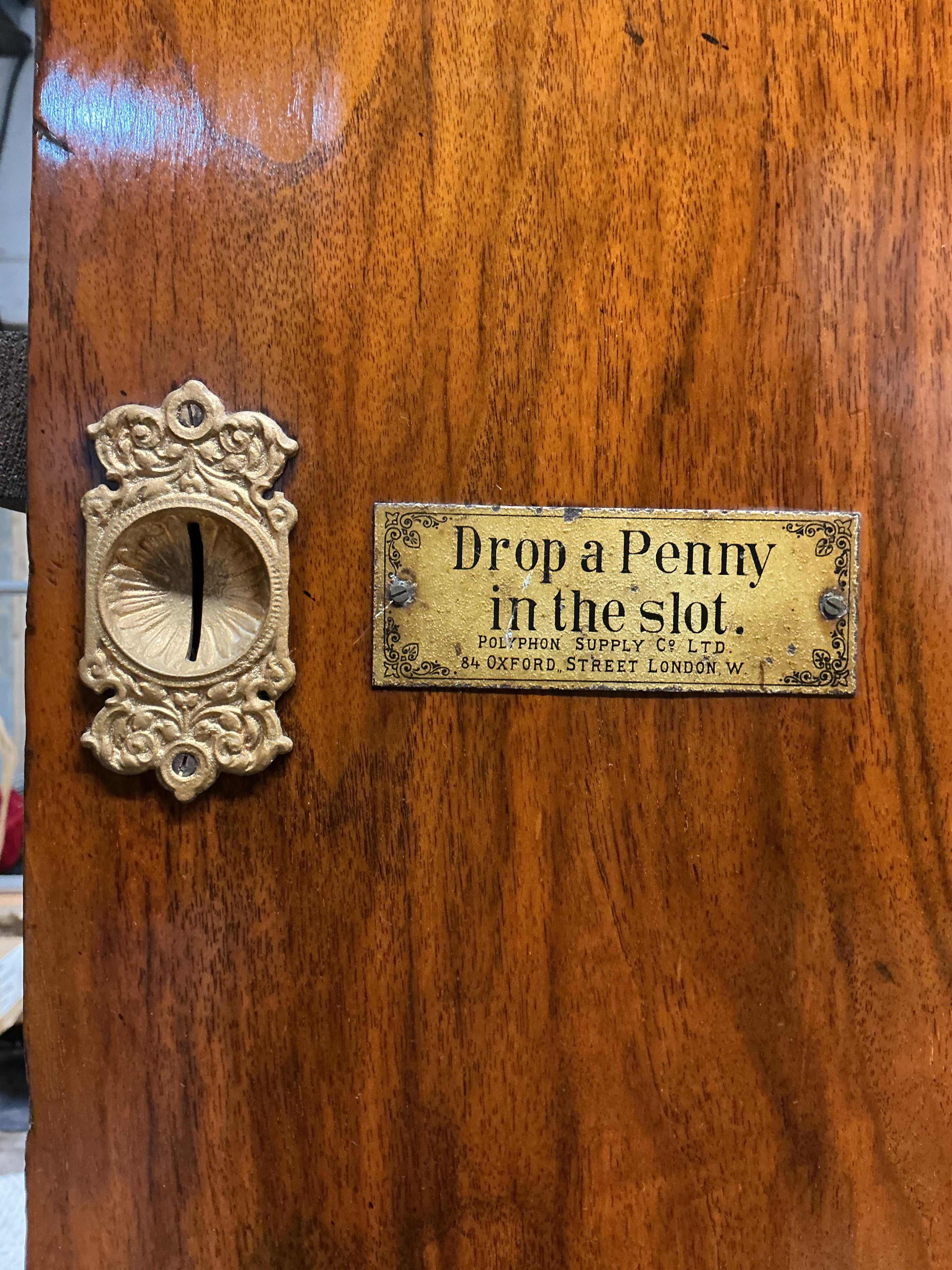A floor standing coin-operated walnut polyphon disc player with nine 50cm diameter discs, the base containing storage compartments for the discs, coin slots on both sides with guilt finished surrounds next to applied lab